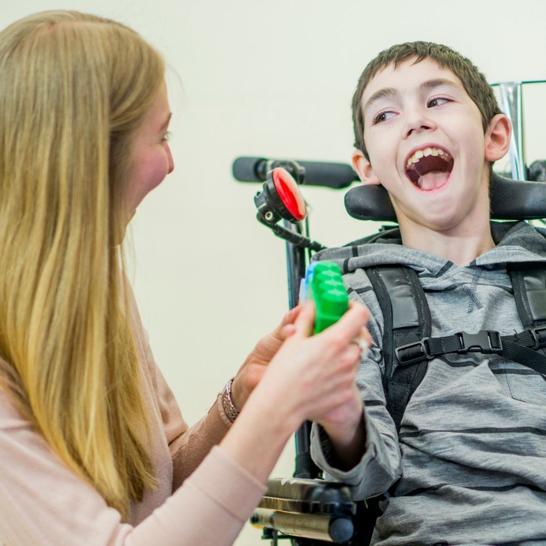 smiling child in wheelchair with woman